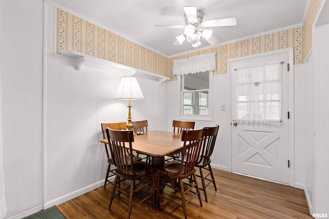 dining area with baseboards, wood finished floors, a ceiling fan, and wallpapered walls