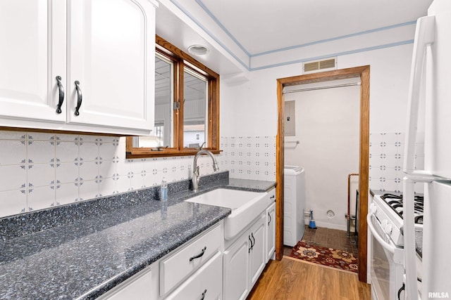 kitchen with visible vents, light wood-type flooring, white cabinets, white appliances, and a sink