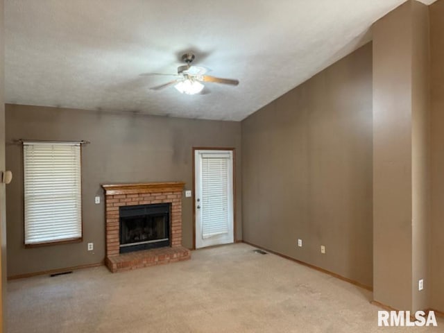 unfurnished living room with a brick fireplace, a textured ceiling, carpet, and a ceiling fan