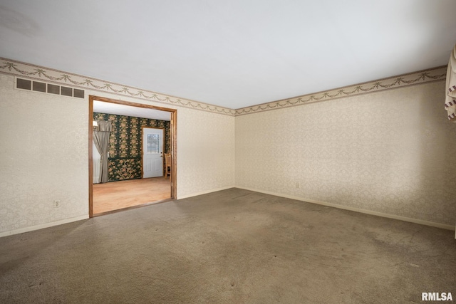 spare room featuring wallpapered walls, carpet flooring, baseboards, and visible vents