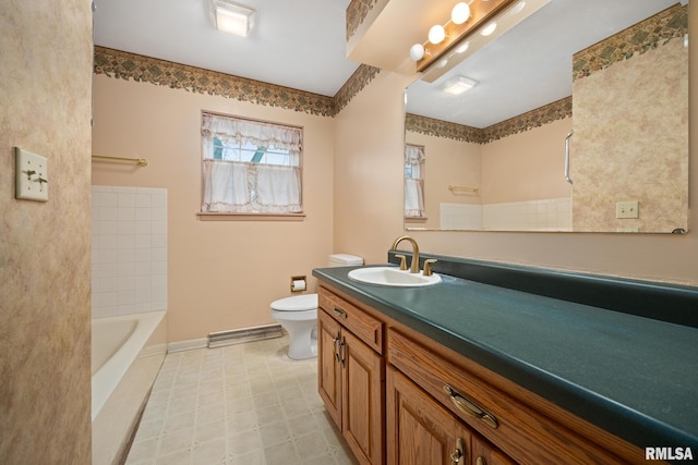 bathroom with vanity, toilet, a bath, and baseboards