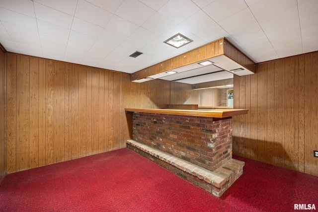 bar featuring wooden walls, a bar, visible vents, and carpet floors