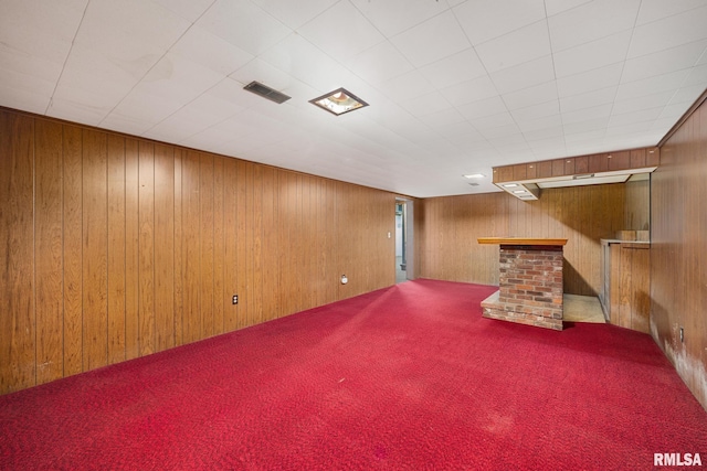 finished below grade area featuring visible vents, carpet floors, and wood walls