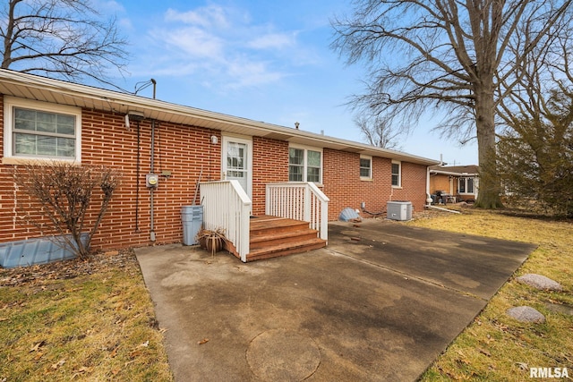 view of front of home featuring brick siding, central air condition unit, and a patio area