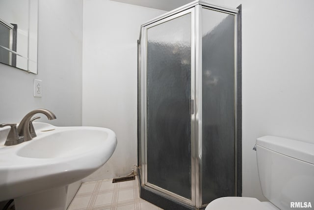 full bathroom featuring tile patterned floors, toilet, a stall shower, and a sink