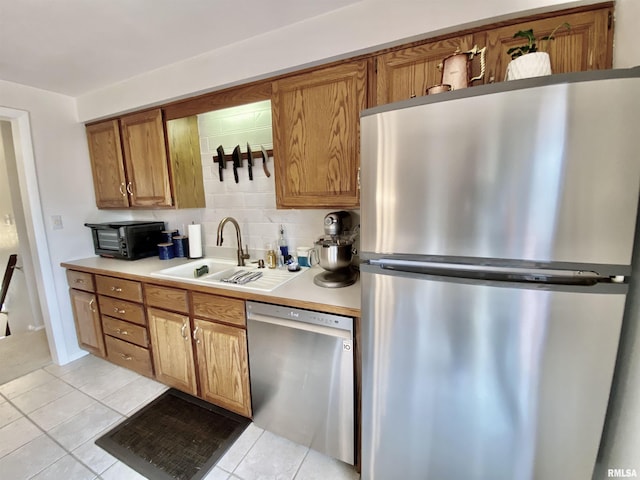 kitchen with light tile patterned floors, backsplash, appliances with stainless steel finishes, and a sink