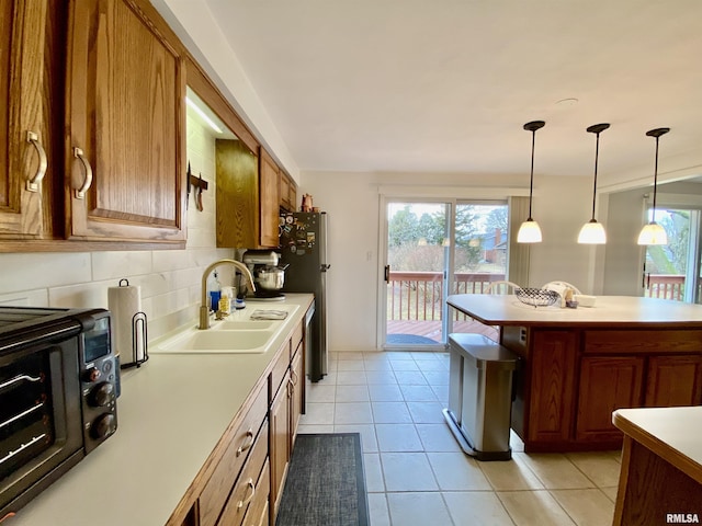 kitchen featuring a wealth of natural light, decorative backsplash, light countertops, and a sink