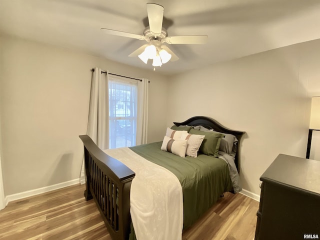 bedroom featuring baseboards, wood finished floors, and a ceiling fan