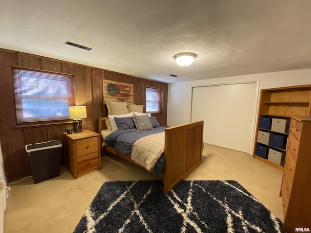 bedroom with visible vents, wood walls, and light colored carpet