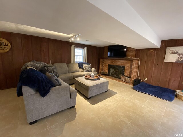 living room with light tile patterned flooring, a fireplace, and wood walls