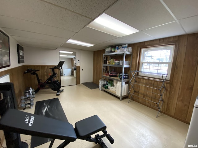 exercise room featuring a drop ceiling and wooden walls