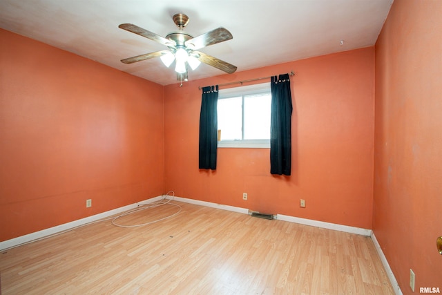 spare room with visible vents, a ceiling fan, baseboards, and wood finished floors