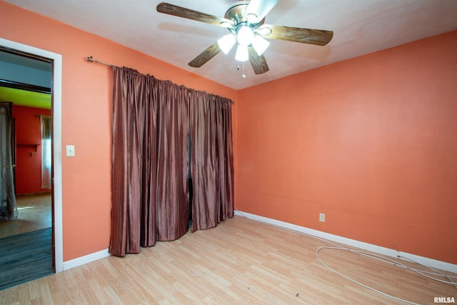 unfurnished room featuring baseboards, wood finished floors, and a ceiling fan