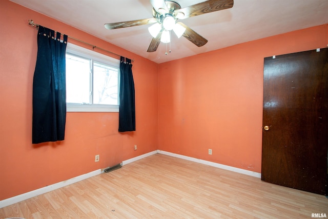 unfurnished room with visible vents, baseboards, wood finished floors, and a ceiling fan