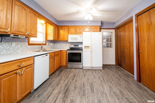 kitchen featuring white appliances, wood finished floors, brown cabinets, and a sink