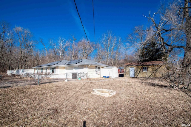 exterior space featuring an outdoor structure, a shed, fence, and roof mounted solar panels