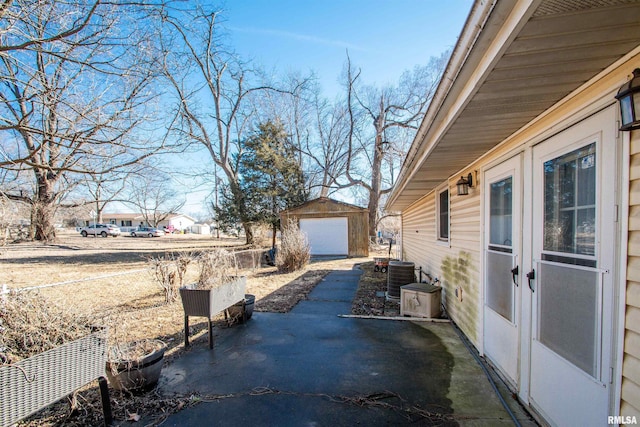 view of patio featuring an outbuilding, a detached garage, and central AC