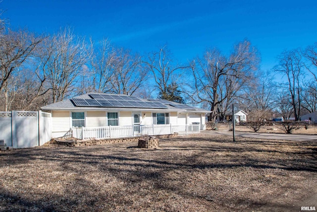 ranch-style home featuring a porch, solar panels, and fence