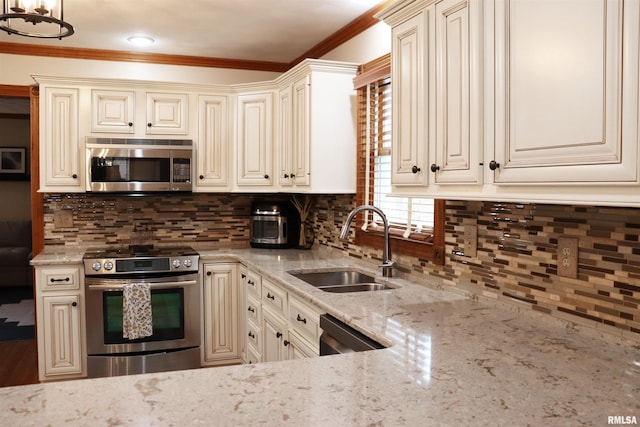 kitchen with a sink, stainless steel appliances, cream cabinets, and ornamental molding