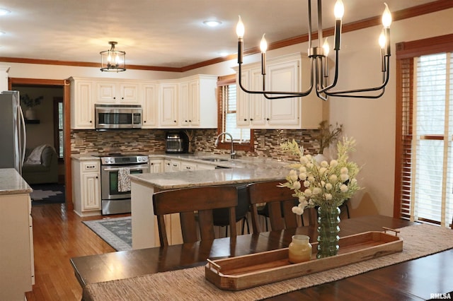 kitchen featuring crown molding, wood finished floors, appliances with stainless steel finishes, and a sink