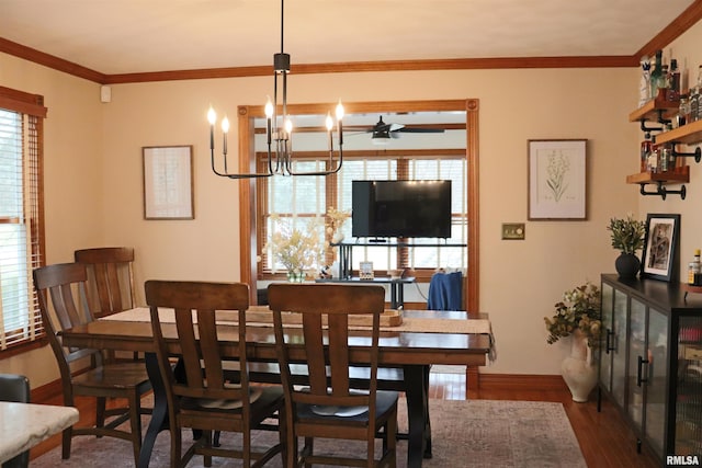 dining room featuring ornamental molding, ceiling fan with notable chandelier, baseboards, and wood finished floors