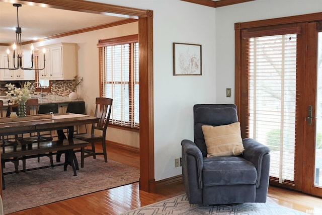 dining space featuring crown molding, baseboards, light wood-type flooring, and a chandelier