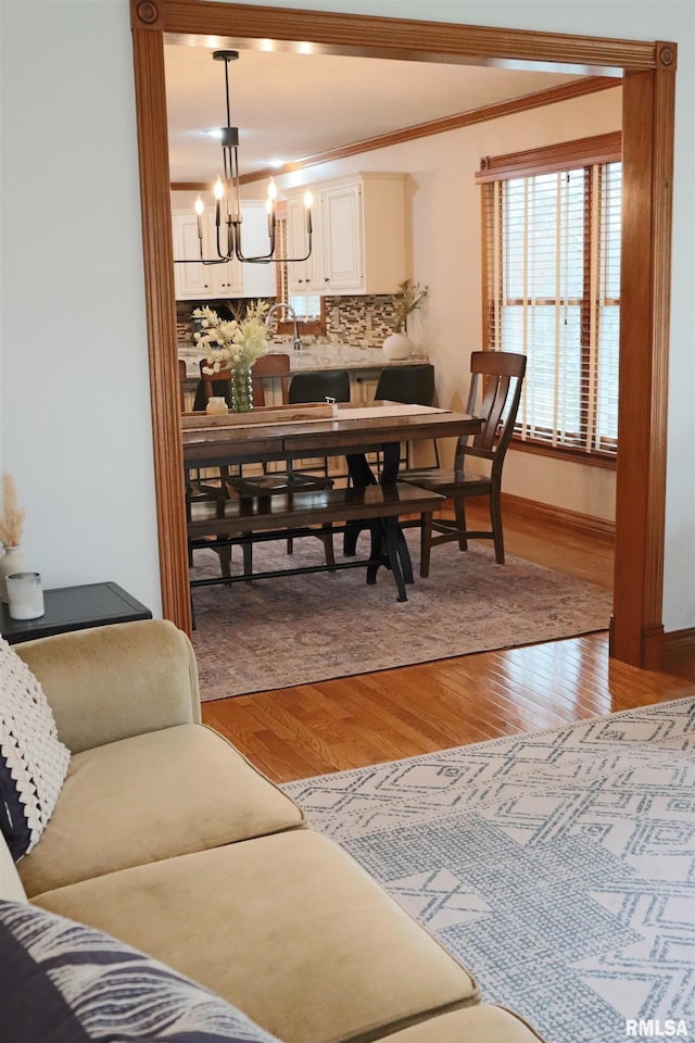 dining room with a notable chandelier, crown molding, baseboards, and wood finished floors