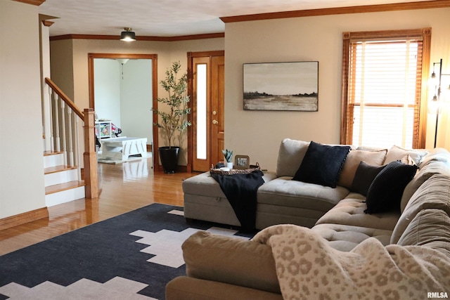 living room featuring stairway, baseboards, wood finished floors, and crown molding