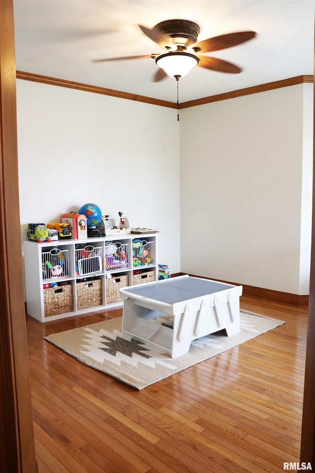 game room with baseboards, crown molding, ceiling fan, and hardwood / wood-style flooring