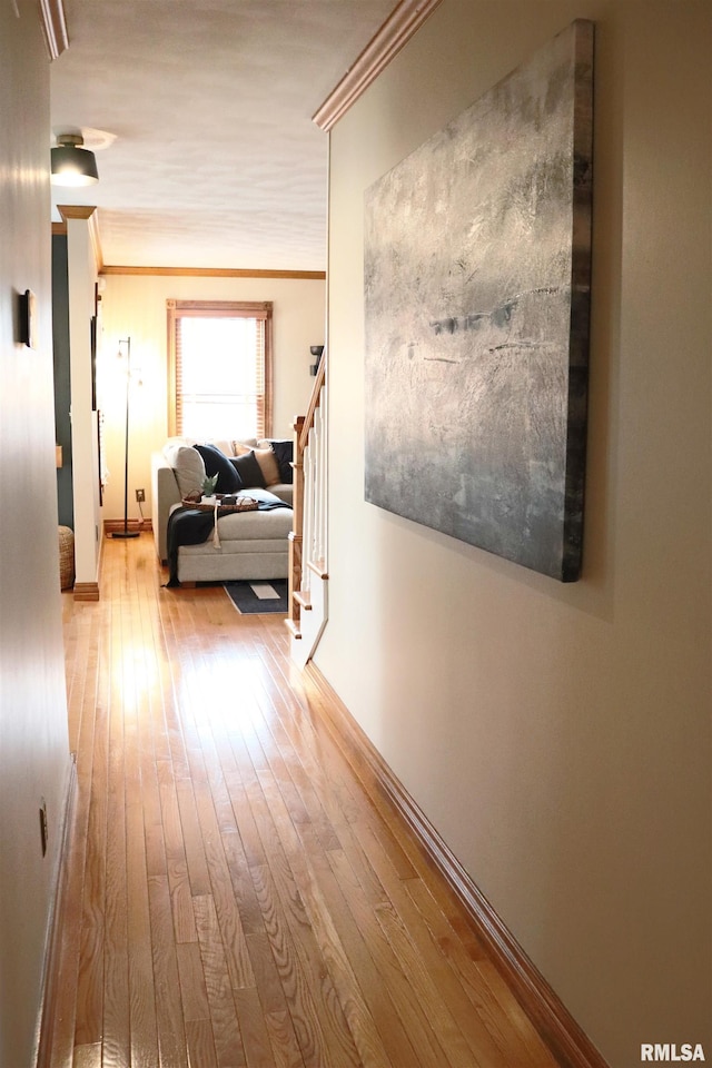 hall featuring stairway, wood-type flooring, baseboards, and crown molding