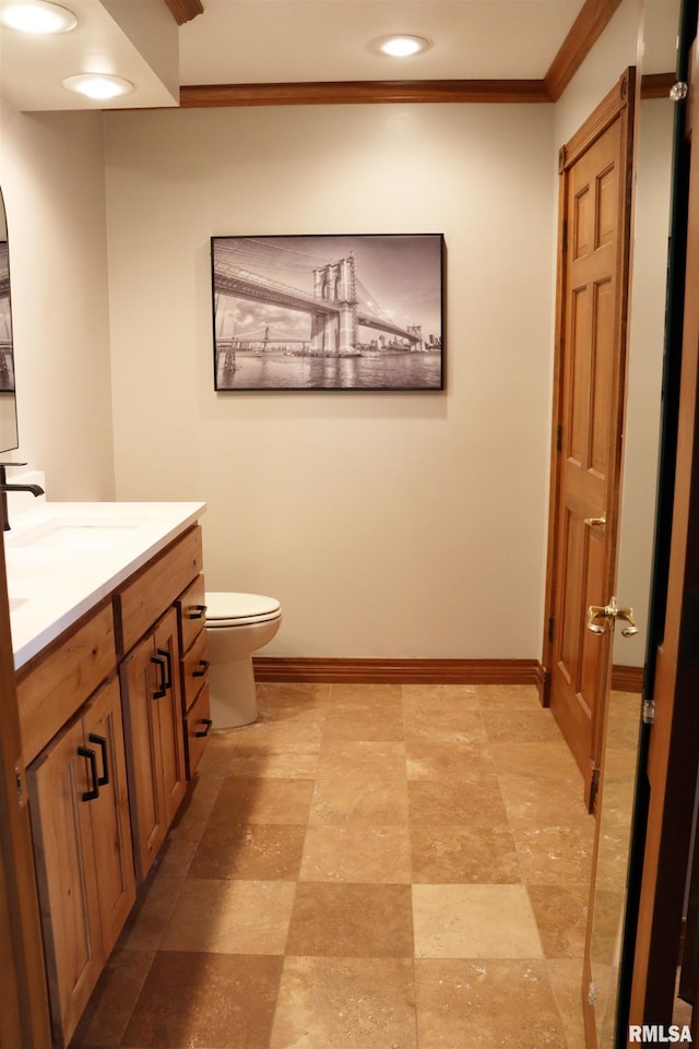 bathroom with vanity, crown molding, toilet, and baseboards