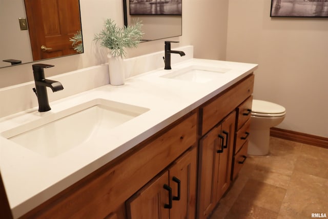 full bath with a sink, baseboards, toilet, and double vanity