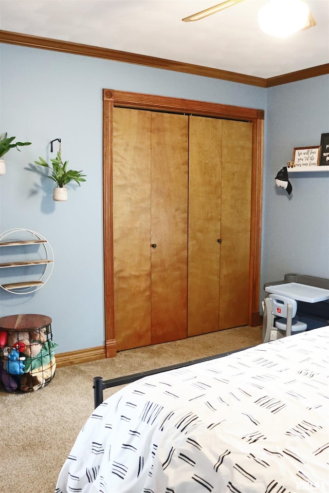 carpeted bedroom with crown molding, baseboards, and a closet