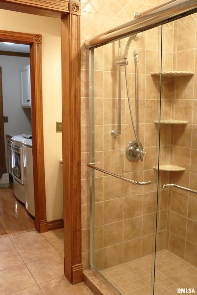 full bath with tile patterned floors, a stall shower, and washer and clothes dryer