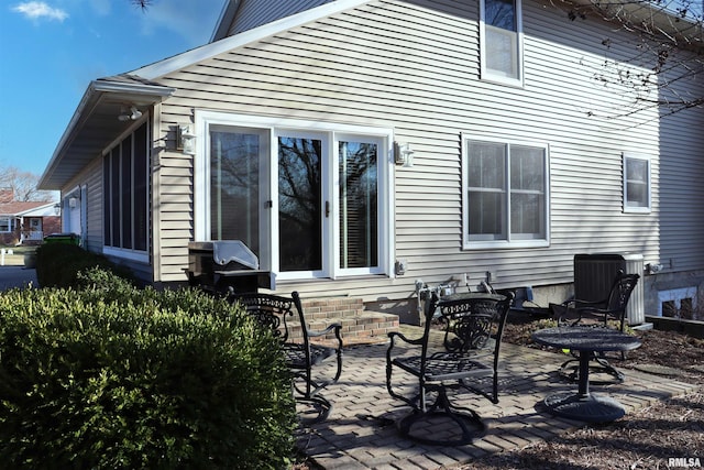 back of property with central air condition unit and a patio