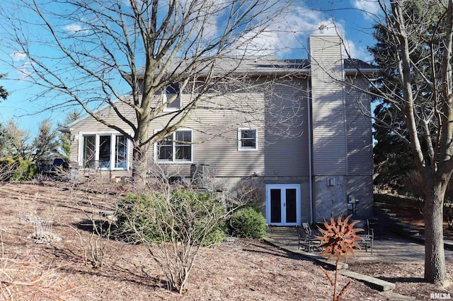 rear view of house with french doors and a chimney