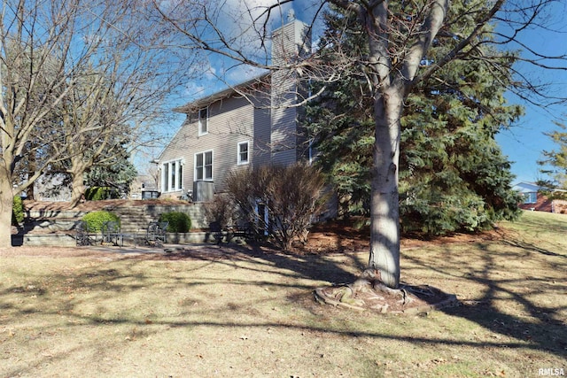 view of side of property with a lawn and a chimney