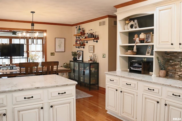 kitchen featuring visible vents, crown molding, a chandelier, light wood-style floors, and open shelves