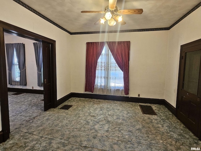 empty room featuring visible vents, carpet floors, baseboards, and crown molding