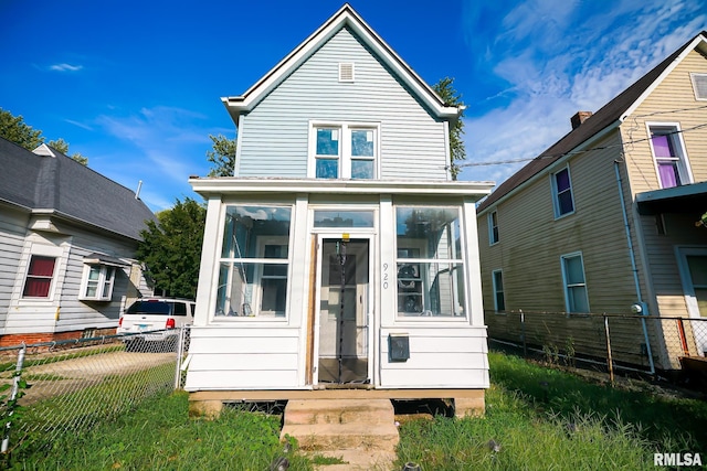 back of property with fence and a sunroom