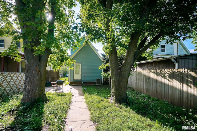 view of yard featuring a patio area, entry steps, central AC unit, and fence