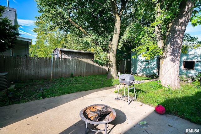 view of patio with area for grilling, a fire pit, fence, and central AC