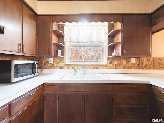 kitchen with stainless steel microwave, light countertops, open shelves, and a sink