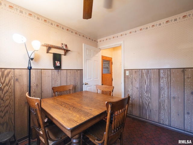 dining room with wainscoting, wallpapered walls, and ceiling fan