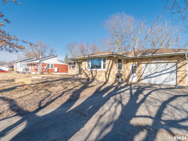 view of front of property with a garage, brick siding, and aphalt driveway