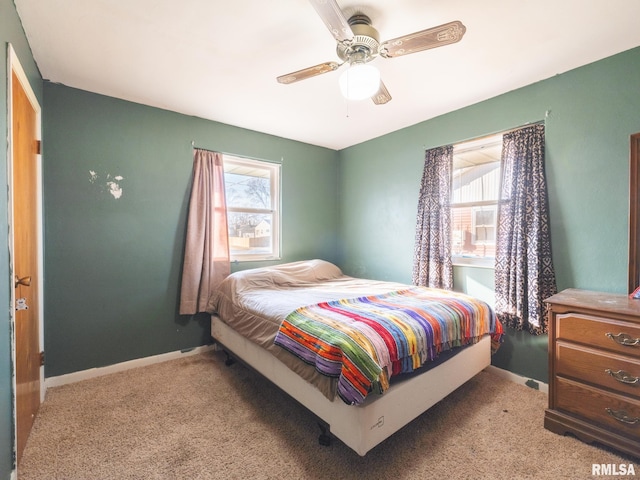 carpeted bedroom with multiple windows, a ceiling fan, and baseboards