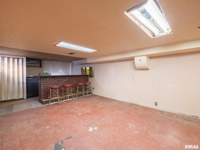 finished below grade area with tile patterned floors, visible vents, an AC wall unit, and a dry bar