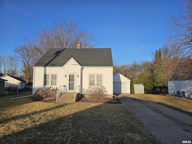 bungalow featuring roof with shingles, an outdoor structure, a front yard, a garage, and a chimney