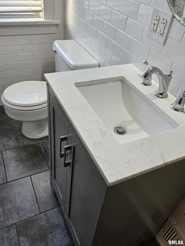 half bathroom featuring toilet, tile walls, and vanity