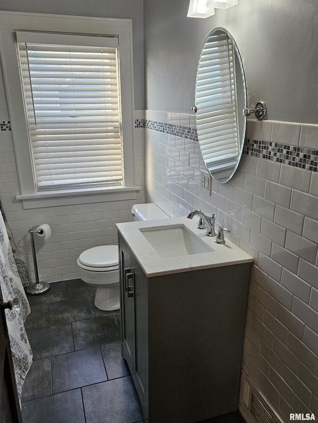 bathroom featuring visible vents, toilet, tile walls, and vanity